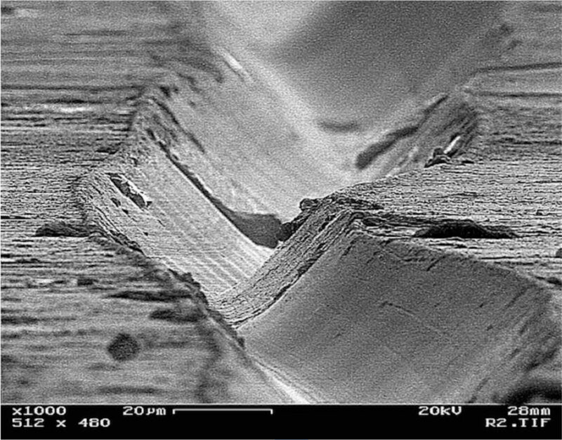 Scanning electron microscope image of a vinyl record groove showing stereo modulations, highlighting the microscopic scale traced by the TESSELLATE Ti Cartridge stylus