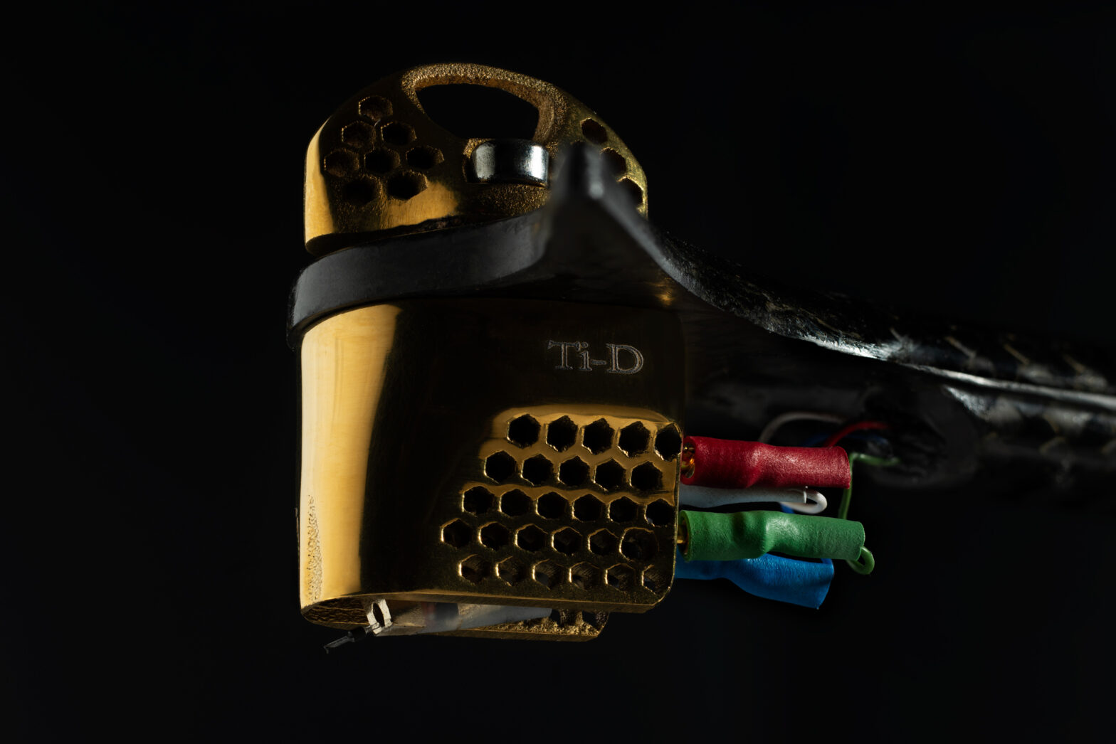 Close-up of the Wilson Benesch TESSELLATE Ti-D Cartridge mounted in the GRAVITON Ti Tonearm, showing its gold titanium tessellated structure, energy transfer interface, and precision-engineered stylus assembly.